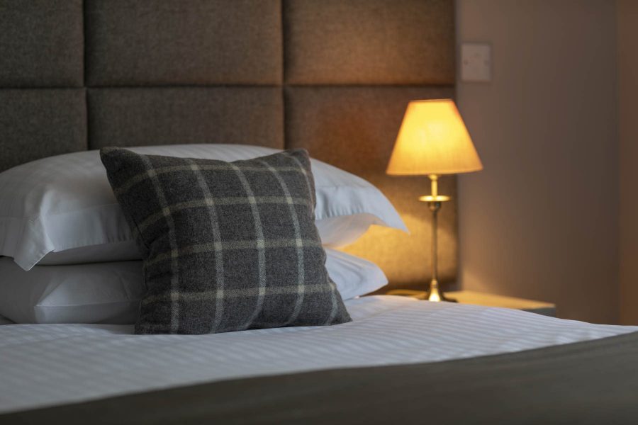 A grey tartan pillow on a bed in one of our Highland guest rooms